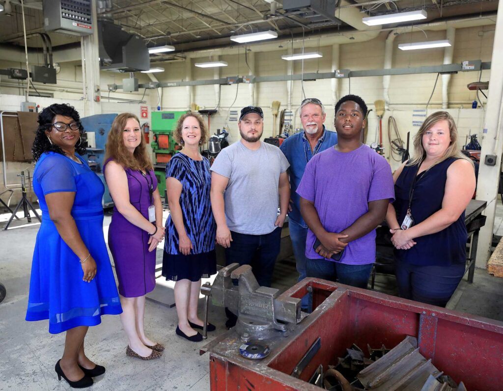Group photo of VersAbility Tech staff and students standing together in a workshop.