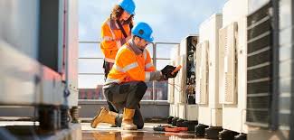 Two men collaborating on the maintenance of a large air conditioning unit outdoors.
